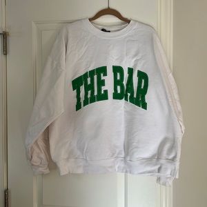 The Bar Best Selling Varsity Sweatshirt in white with Kelly green writing.